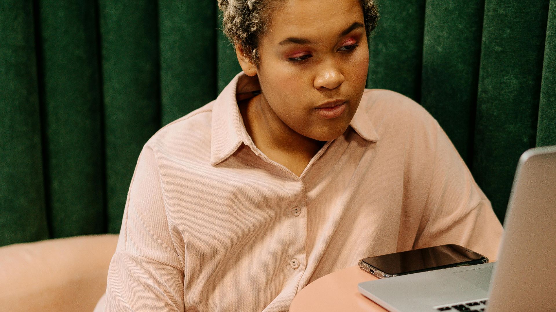 African American woman in casual attire focused on work at a table.