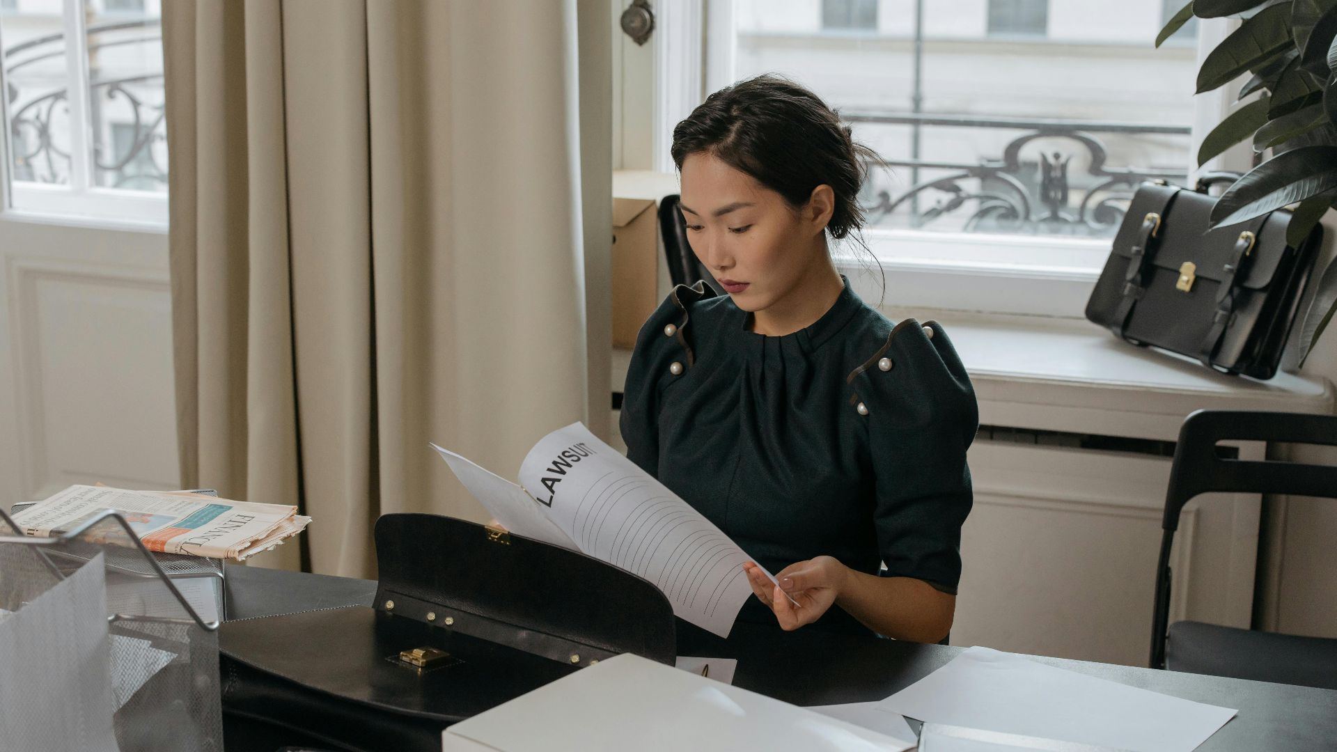 Elegant young woman reading documents in a stylish office setting.