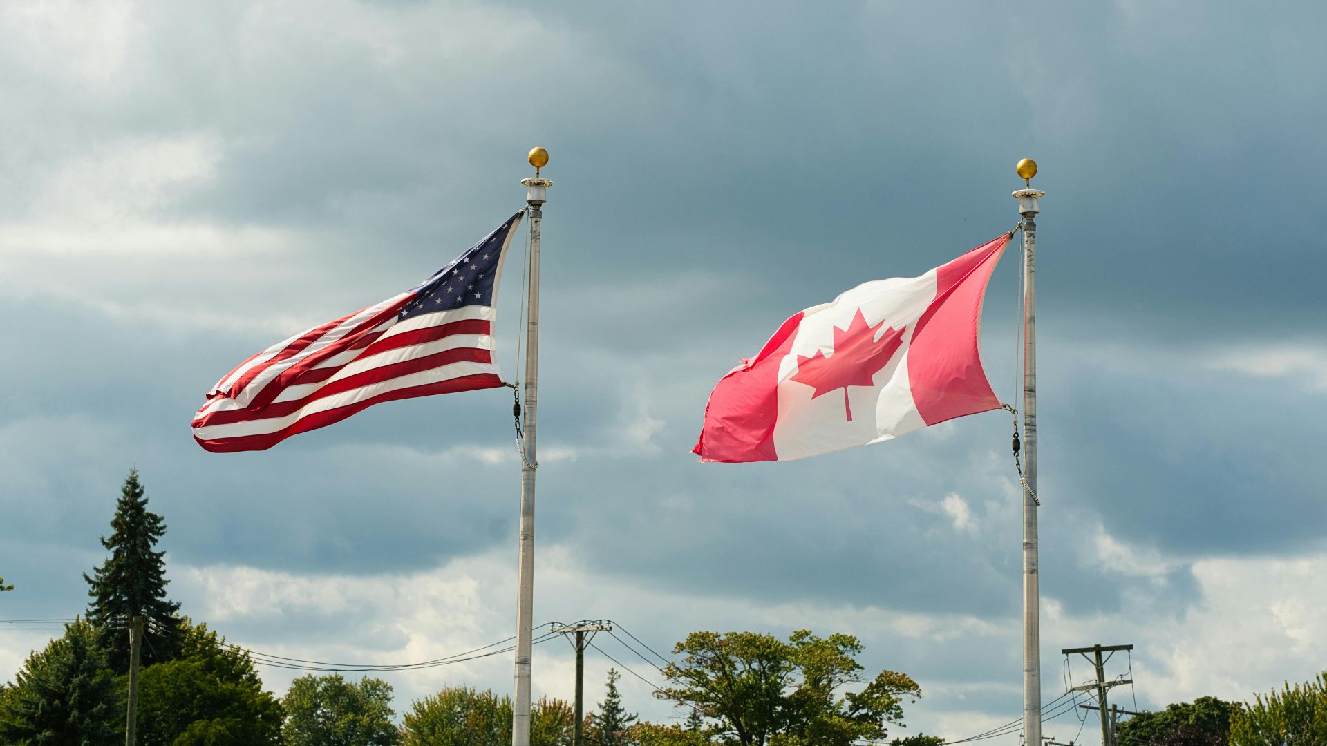 Canadian and American flags waving under a cloudy sky in Harbor Beach, MI.