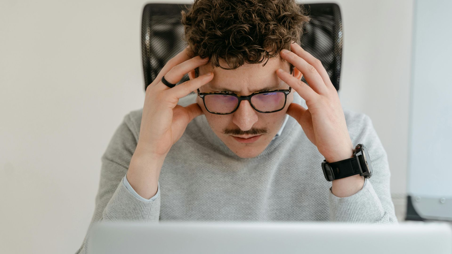 A serious businessman focusing intently on his work, using a laptop indoors.