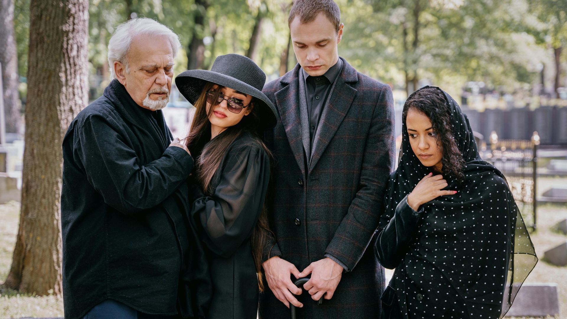 Group reflecting loss during a somber cemetery gathering.