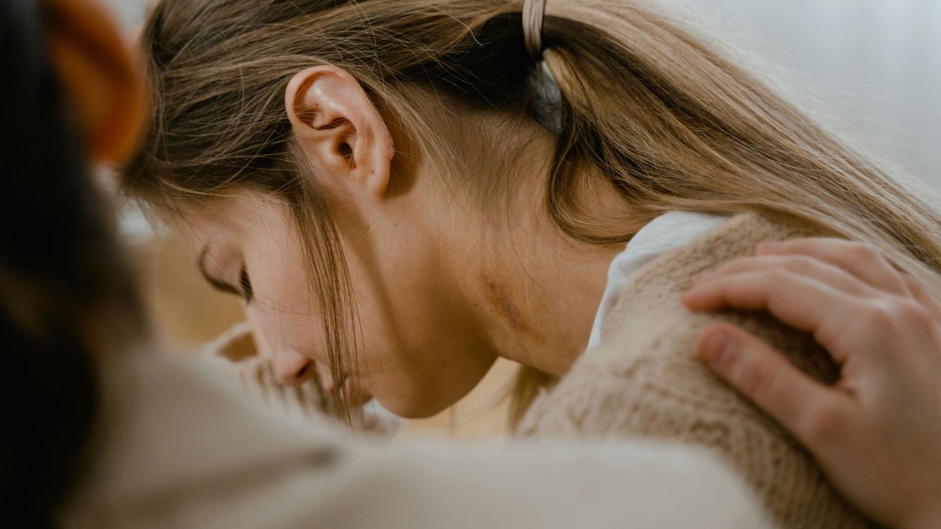 An emotional moment showing a comforting gesture with a hand on a woman's shoulder.