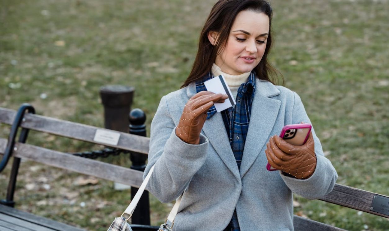 Glad woman making online payment via smartphone in spring park