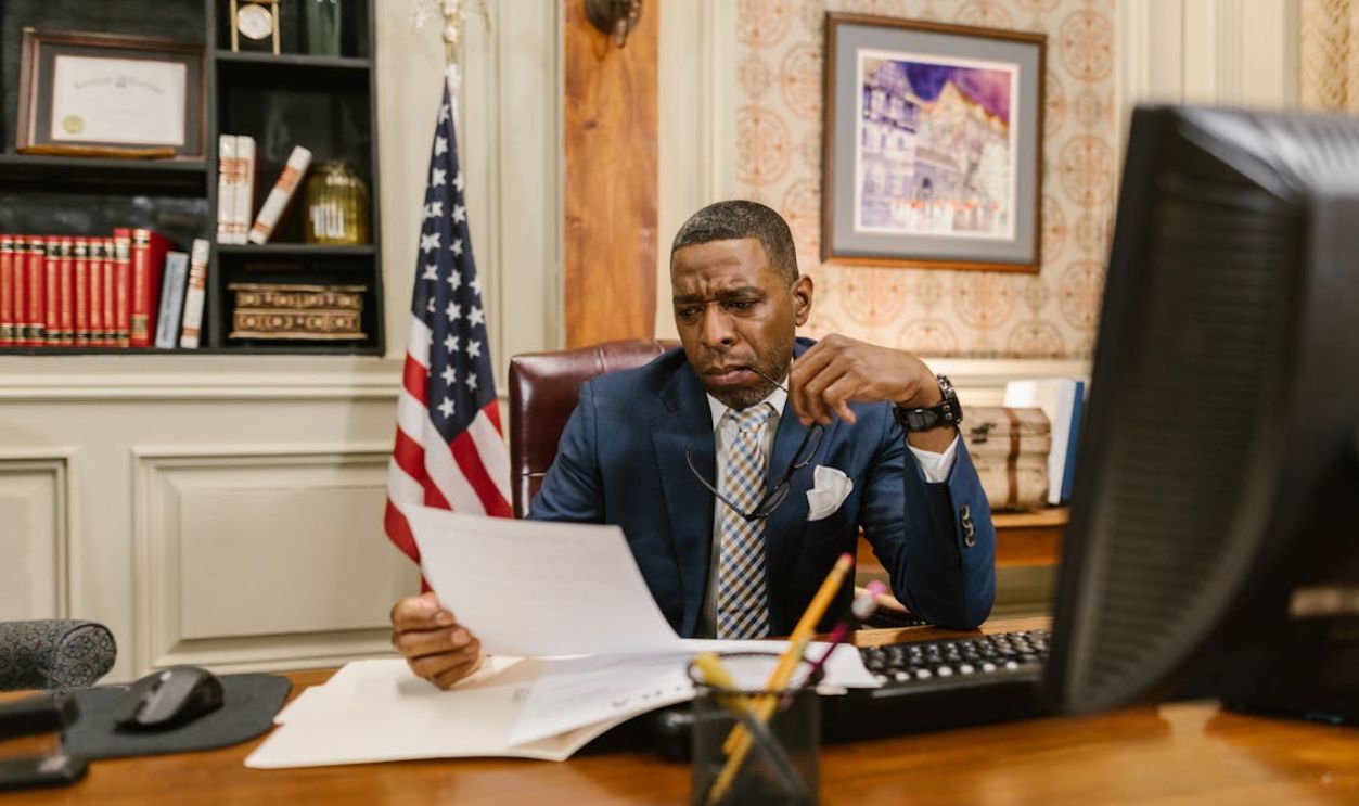 A Man in Blue Suit Jacket Holding White Printer Paper