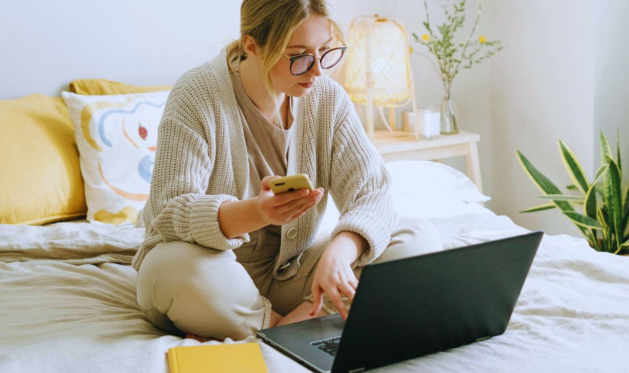 Photo of Woman Sitting on Bed While Using Black Laptop
