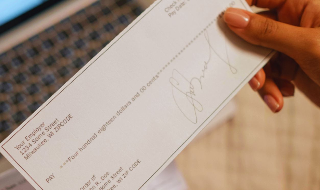 A Person's Hand Holding a Cheque