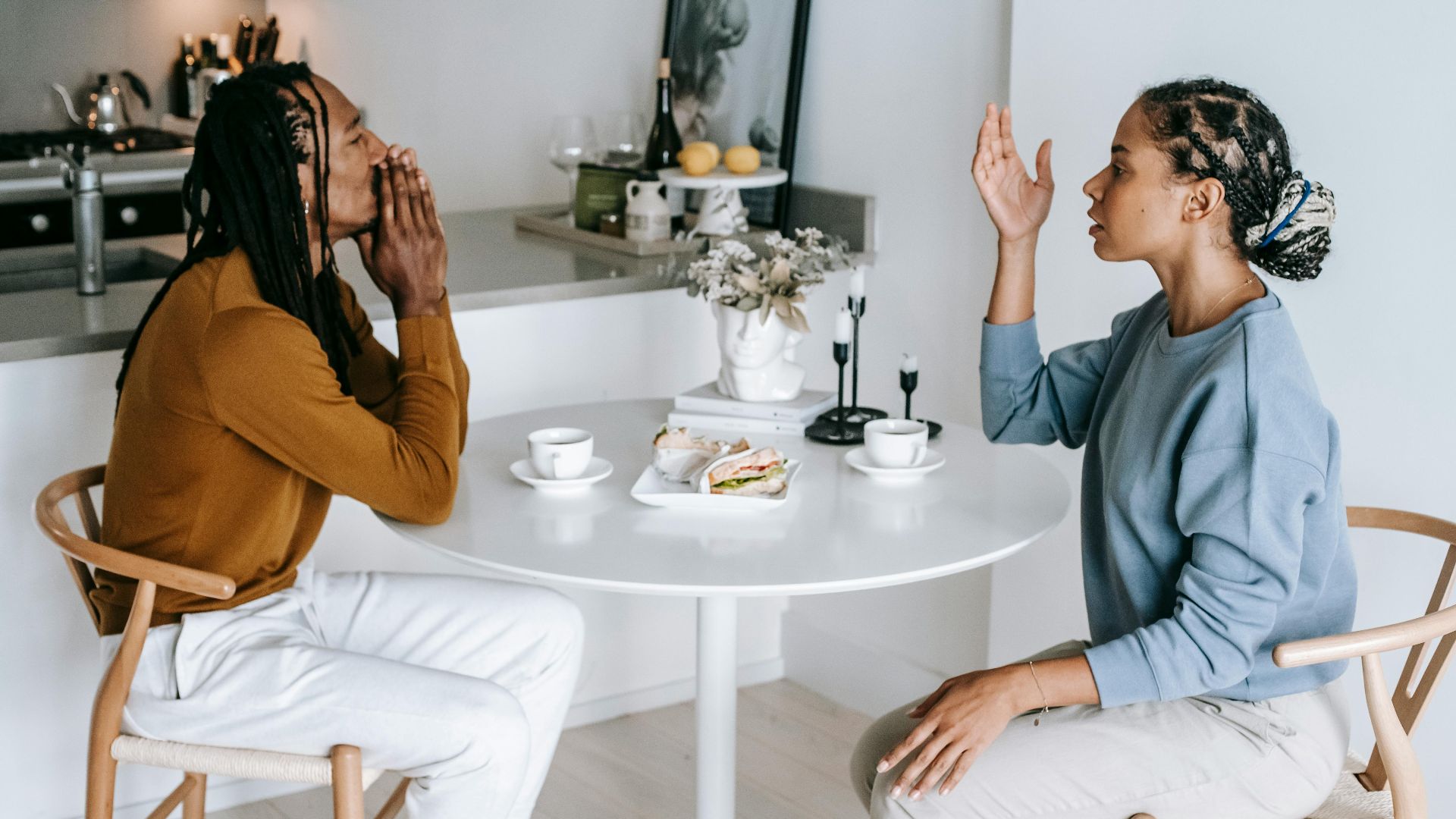 A couple in an intense conversation at a kitchen table, highlighting relationship dynamics.