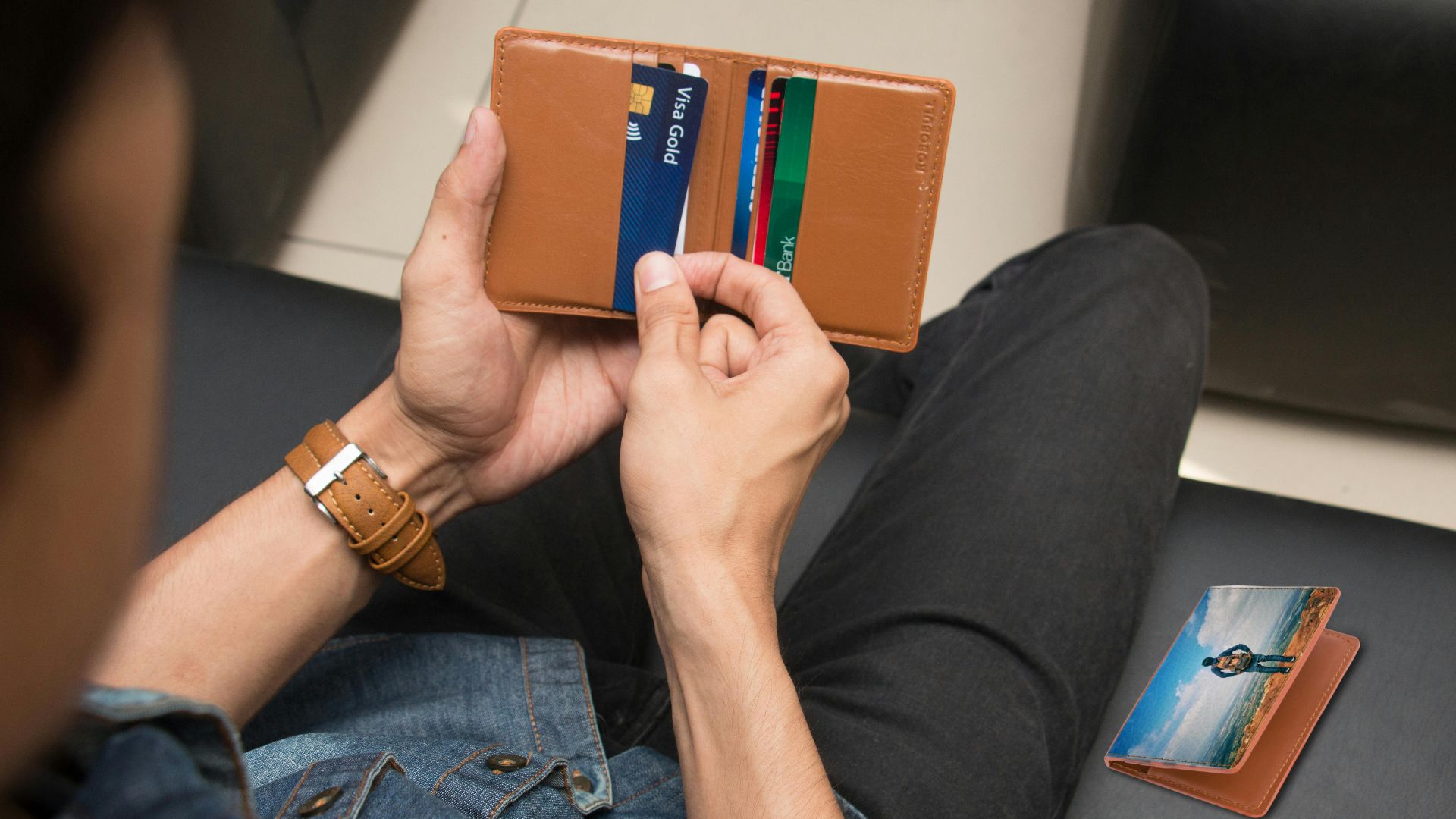 A close-up of a man holding a wallet containing credit cards and an ID inside a room.