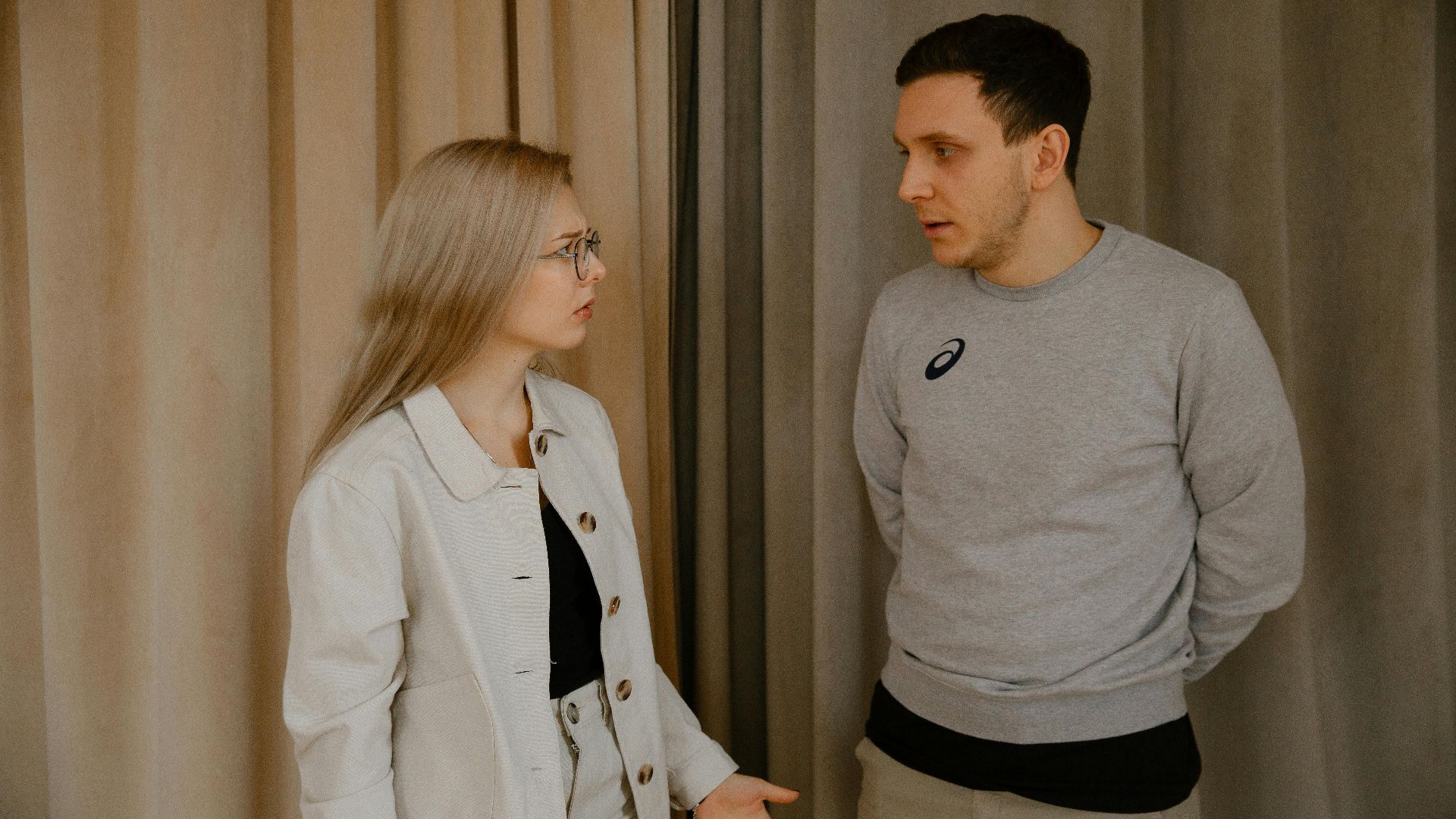 Man and woman having a serious conversation indoors, focused expressions.