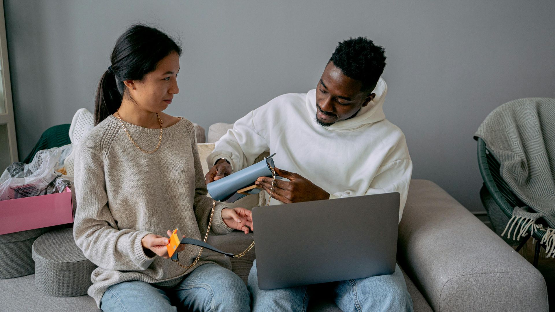 Diverse couple making an online purchase using a laptop and credit card in cozy setting.