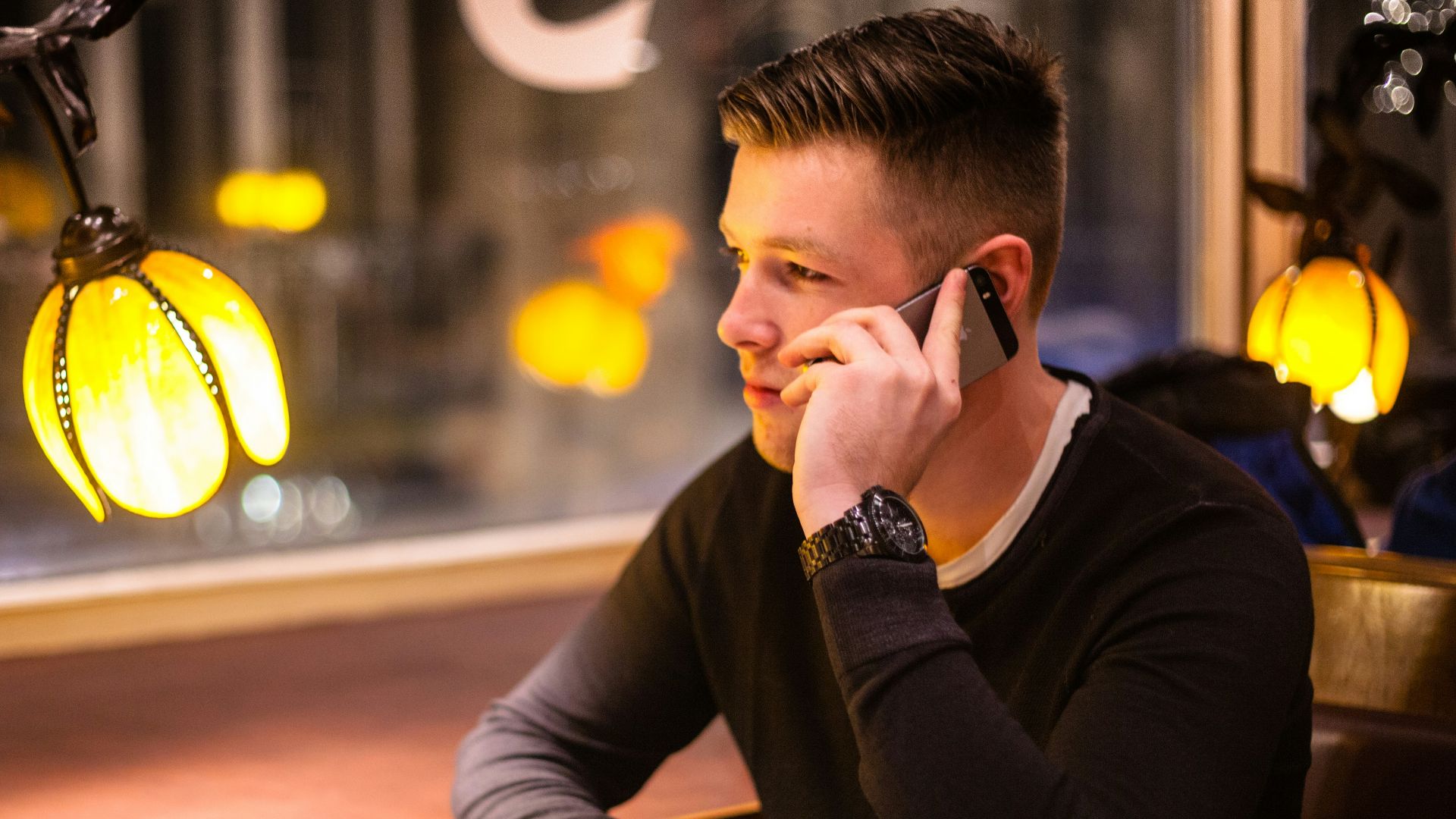 man sitting at the table while using smartphone