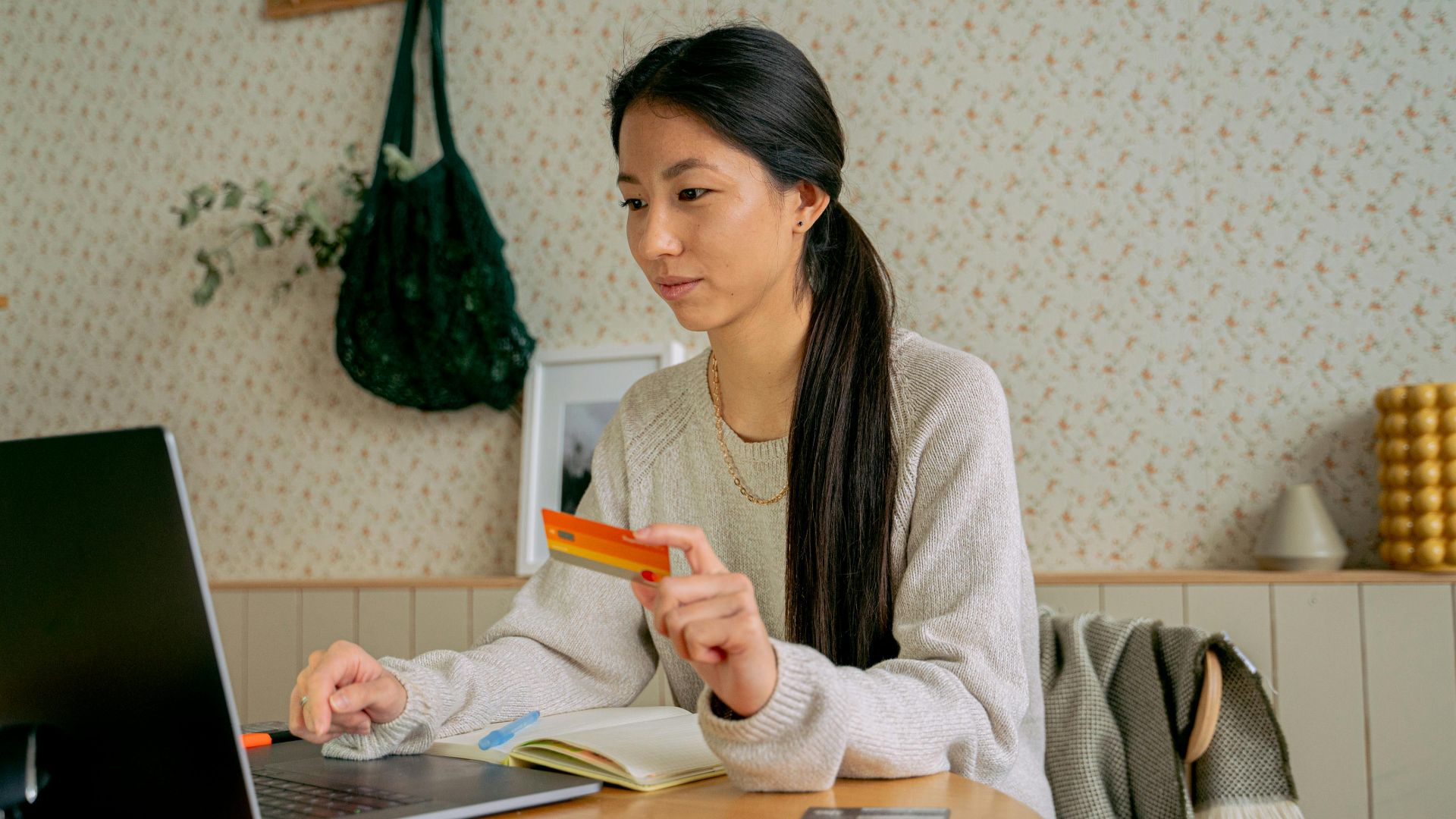 Young Asian woman using a laptop and credit card for online shopping at home.
