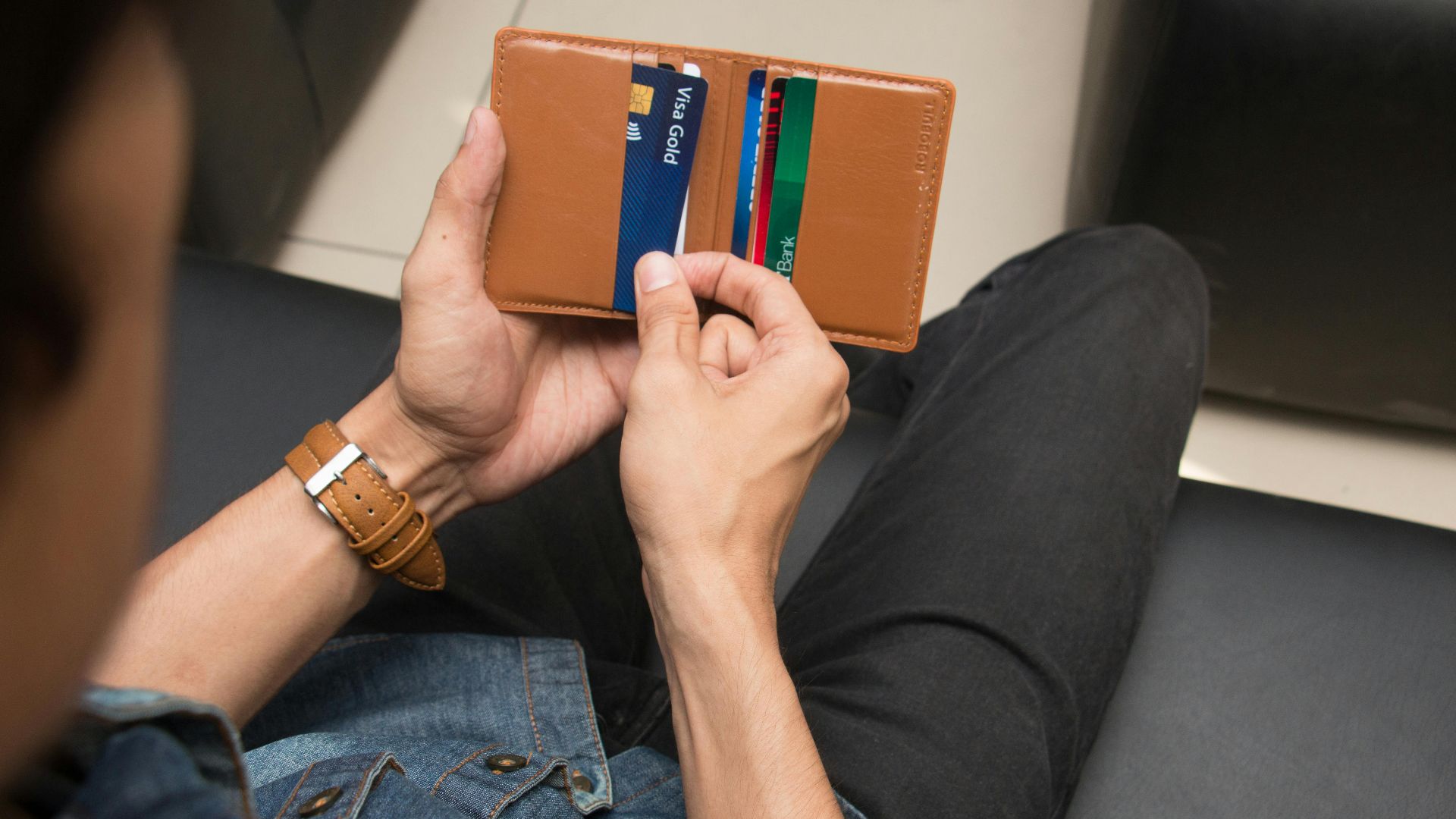 Close-up of a man holding a wallet with various credit cards, showcasing everyday finance essentials.