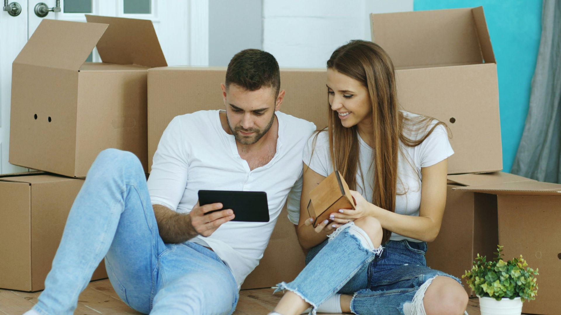 Couple looking at tablet surrounded by moving boxes