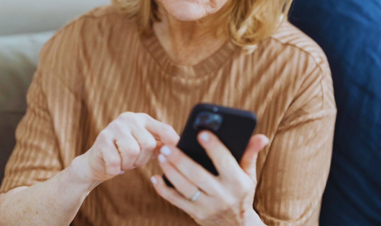 Elderly woman chatting on smartphone on sofa at home