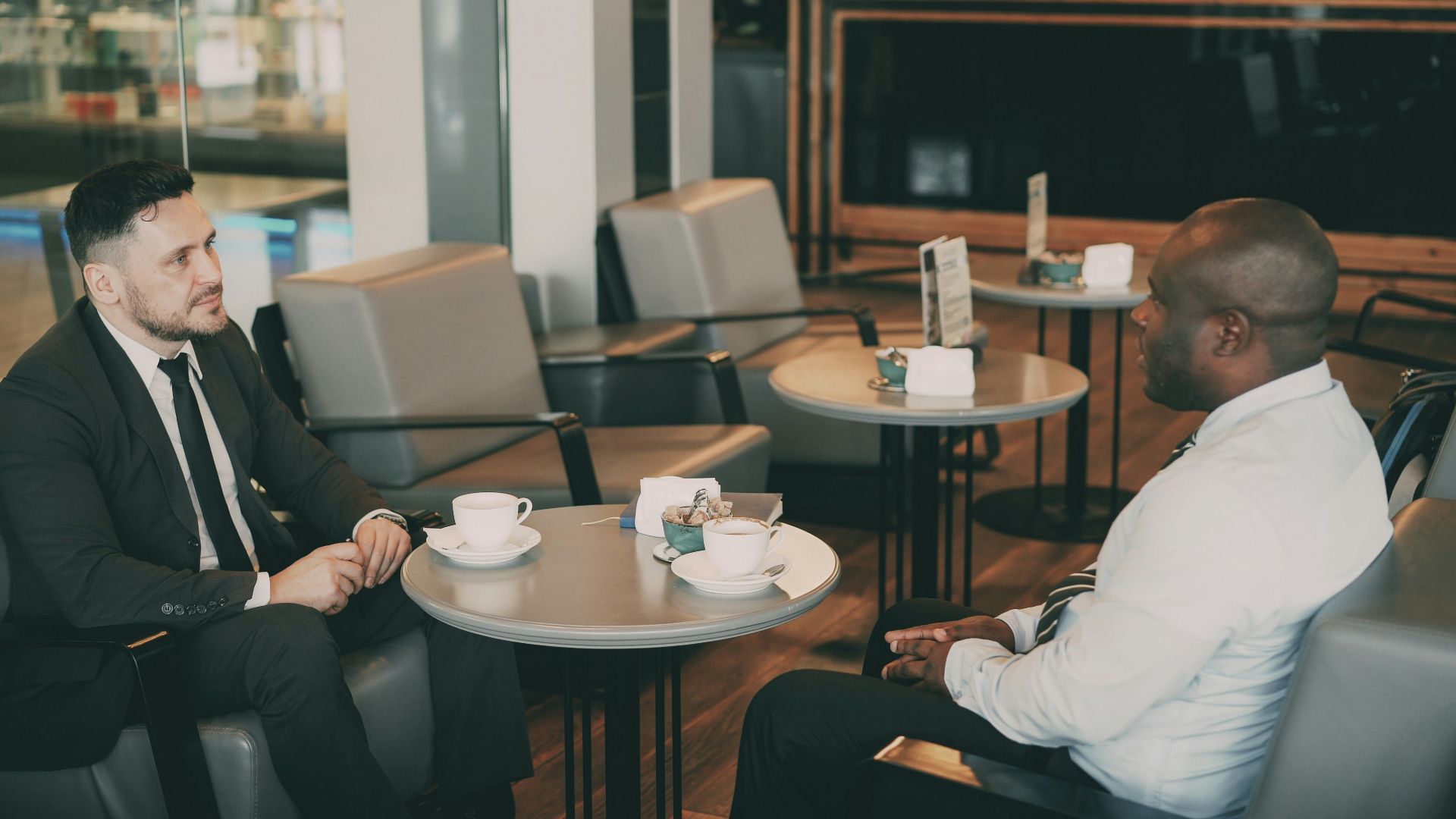 Two men in suits talking at a cafe