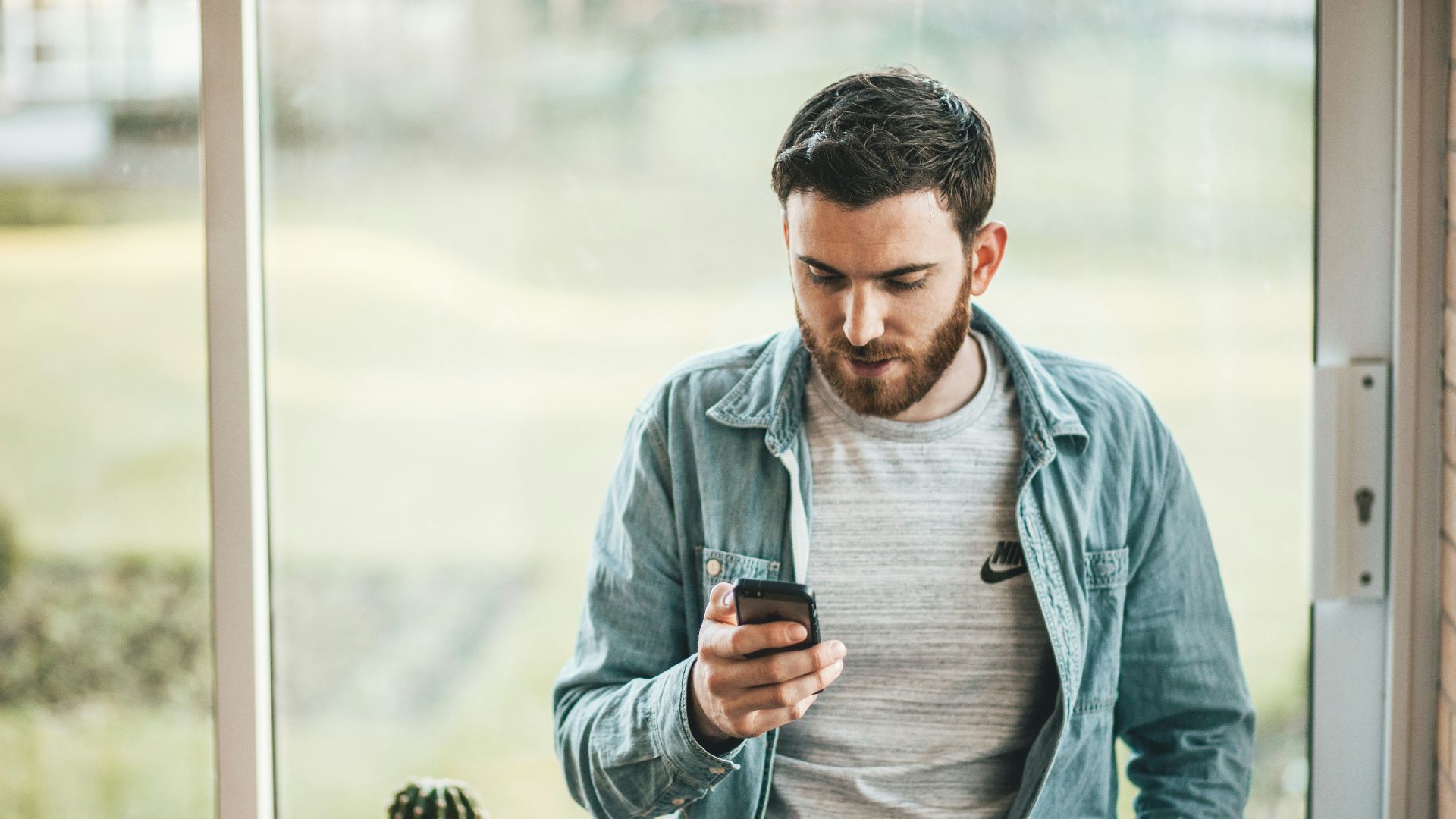 man holding a smartphone near the window