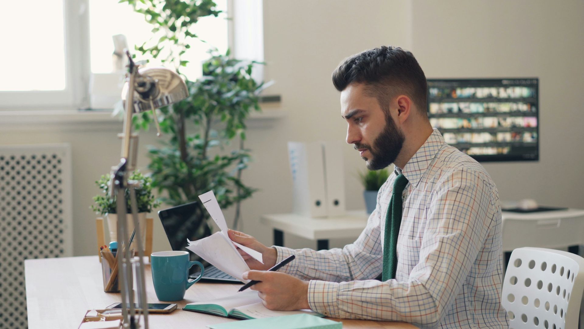 a man sitting at a desk with a laptop and papers