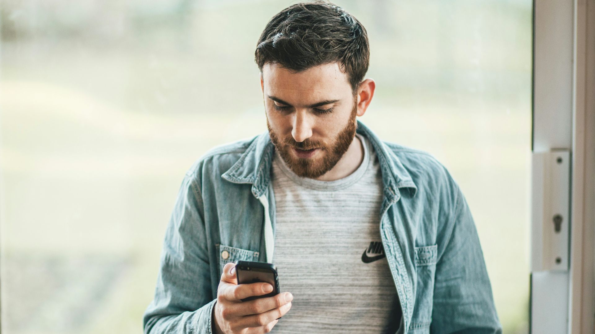 man holding a smartphone near the window