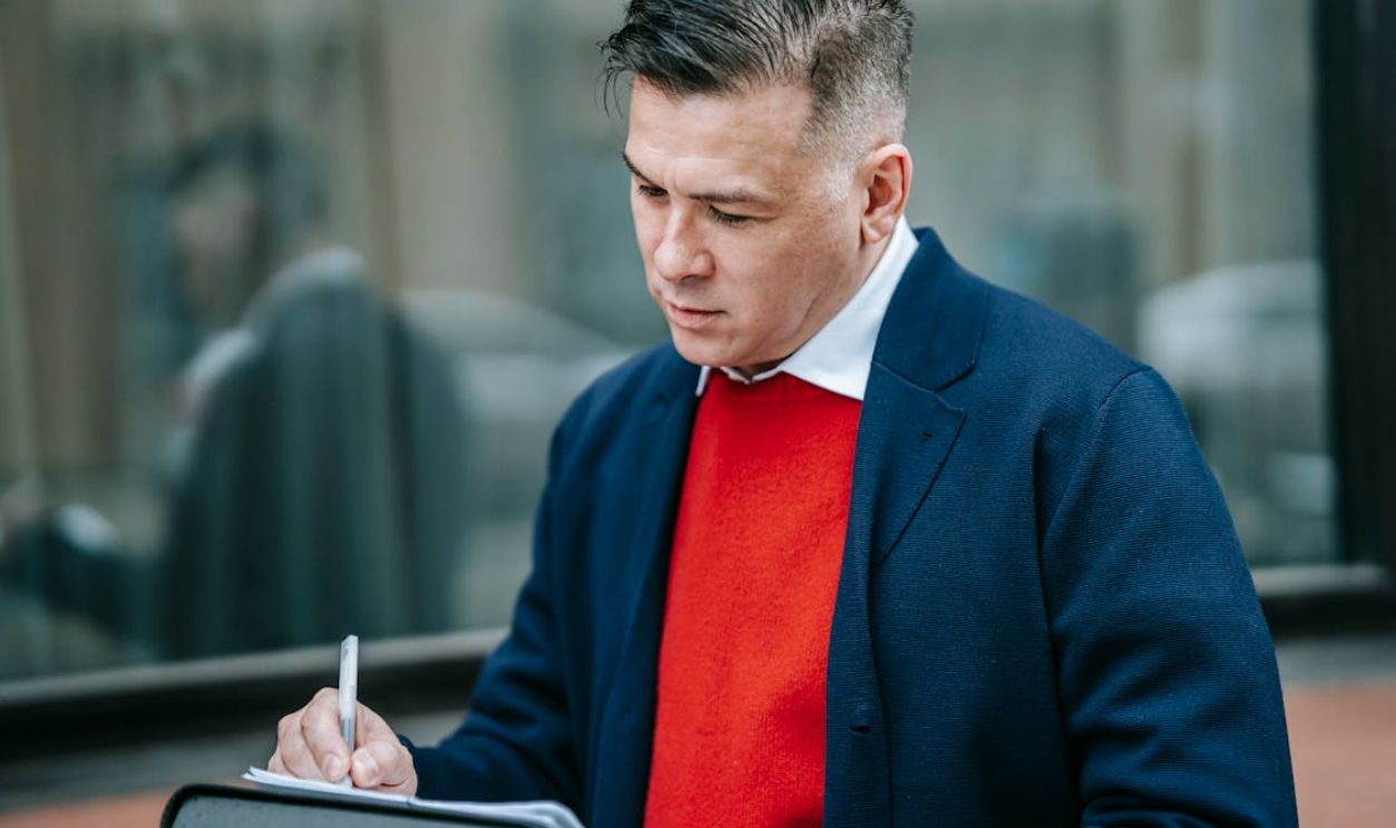 Photo Of Man Writing On Document
