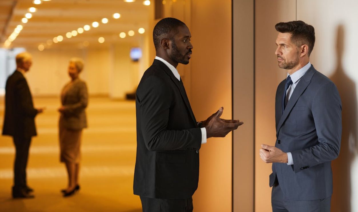 A Man in Black Suit Jacket Talking to a Man in Blue Suit Jacket