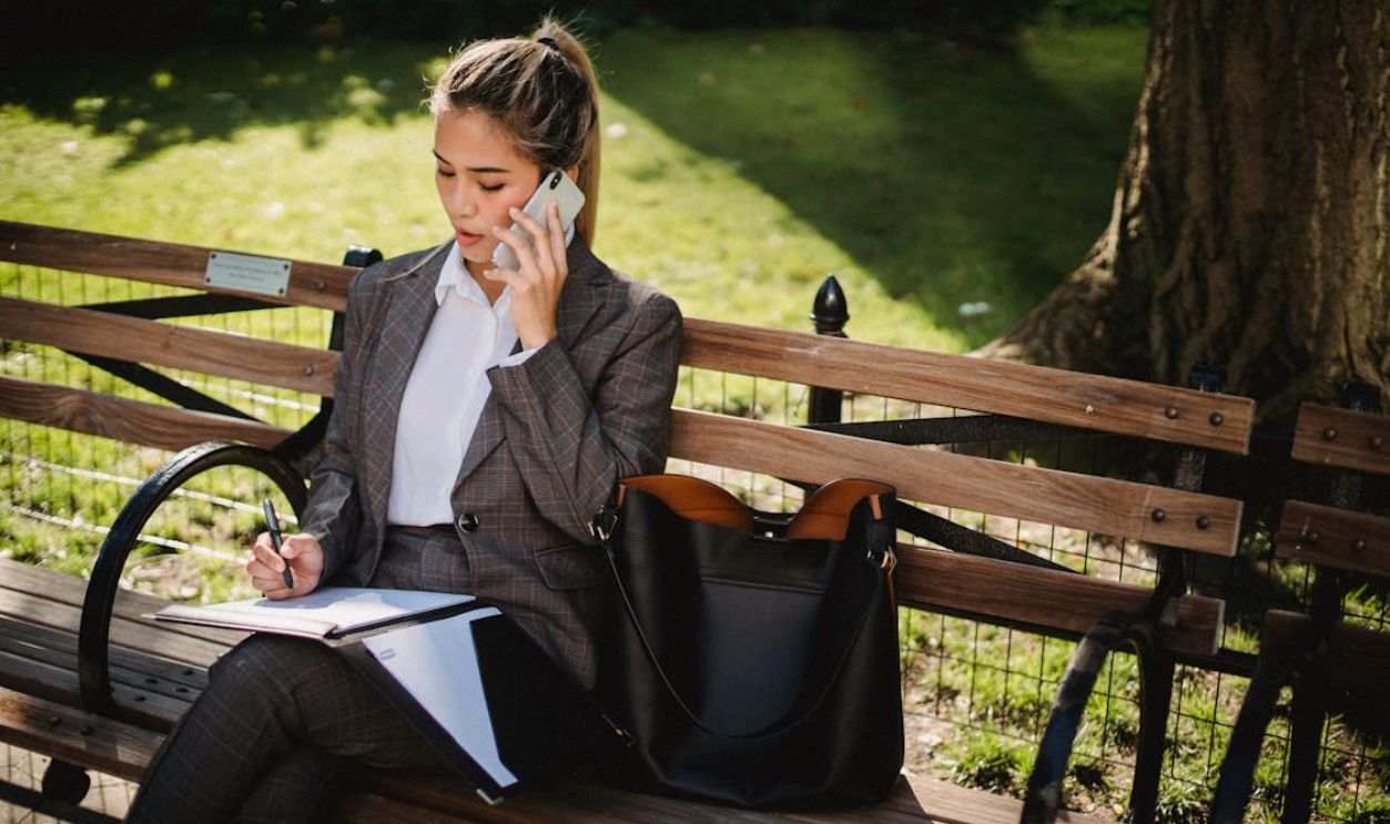 Young Woman in Business Suit Sitting on Bench in Park