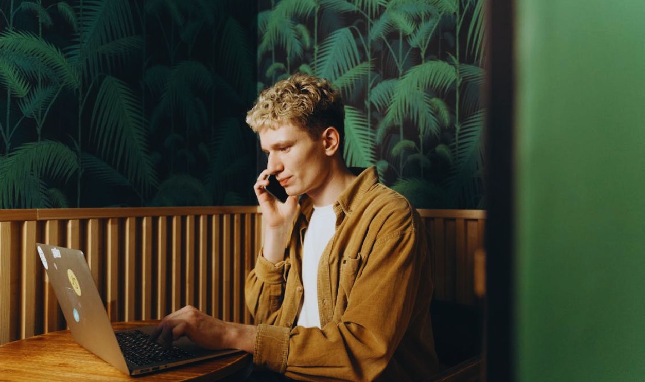 Man in Talking on the Phone While Using a Laptop
