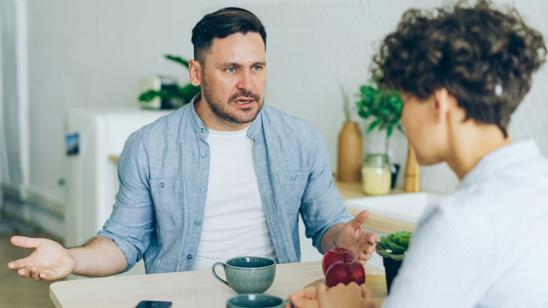 a man sitting at a table talking to a woman