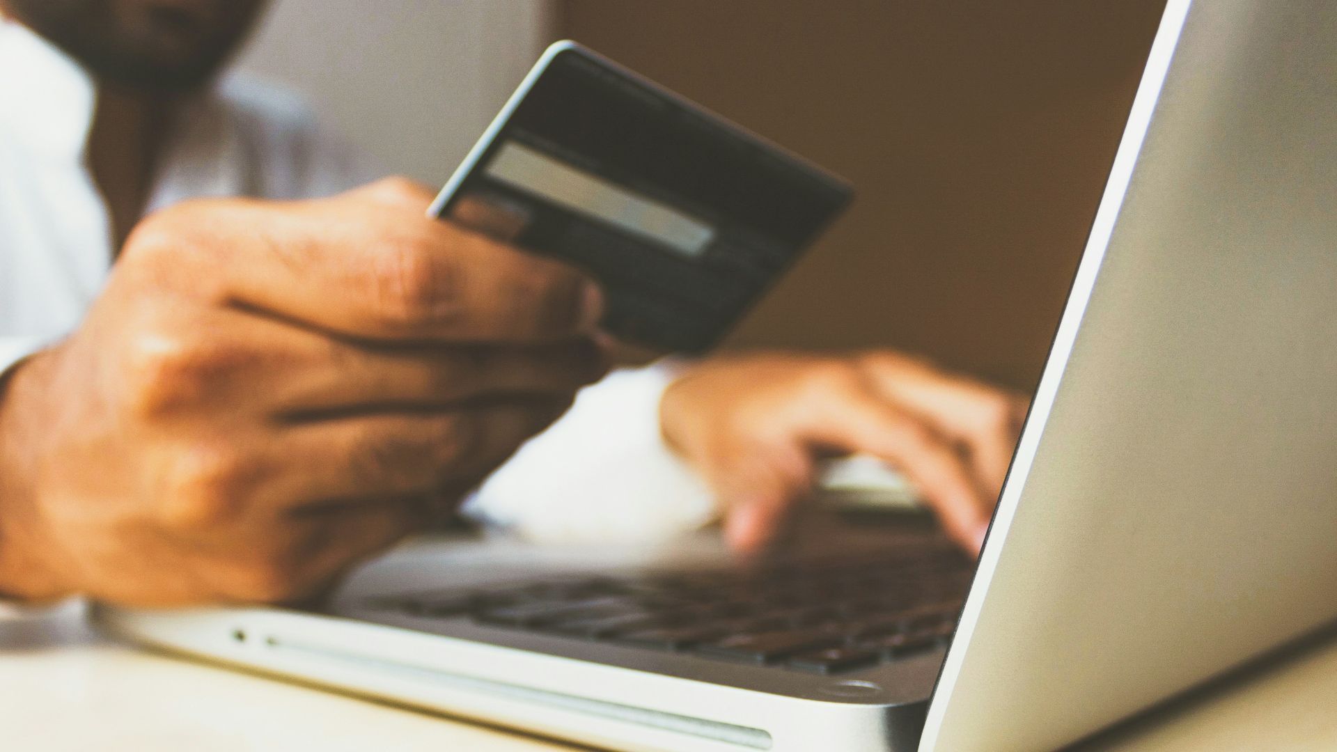 person using laptop computer holding card