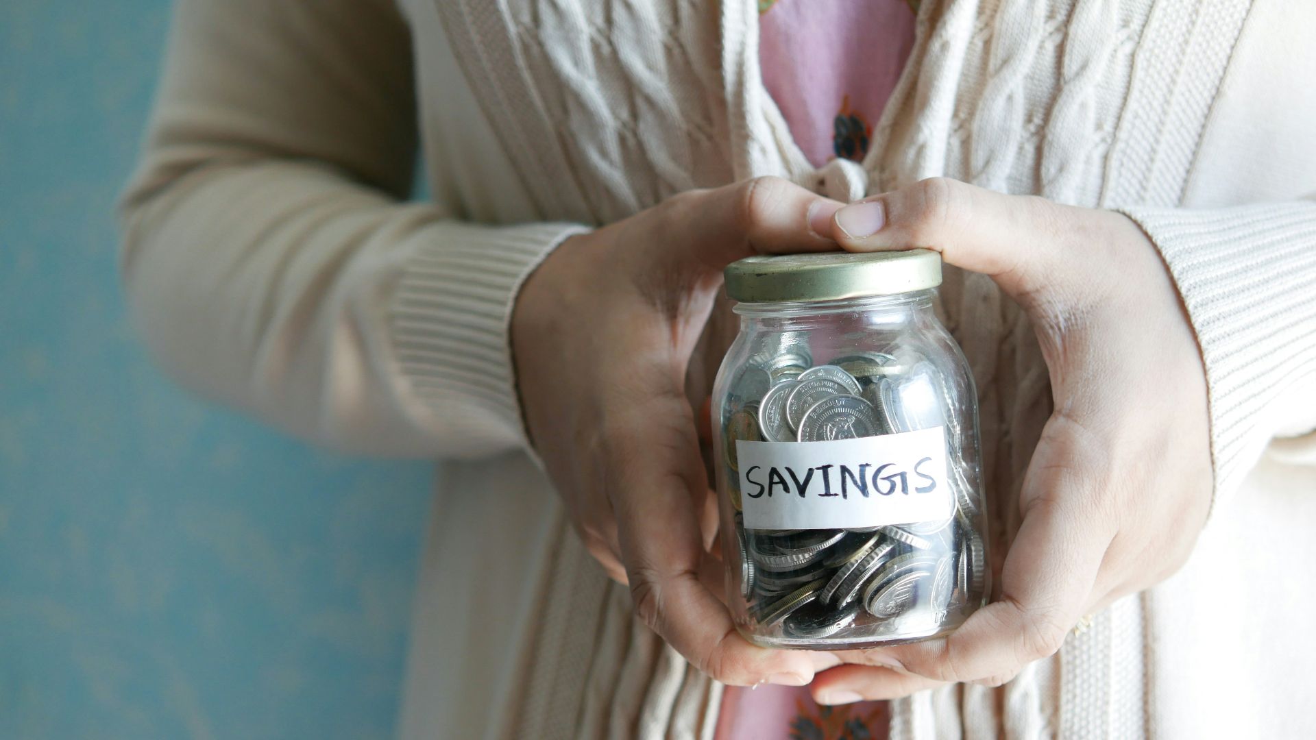 a woman holding a jar with savings written on it