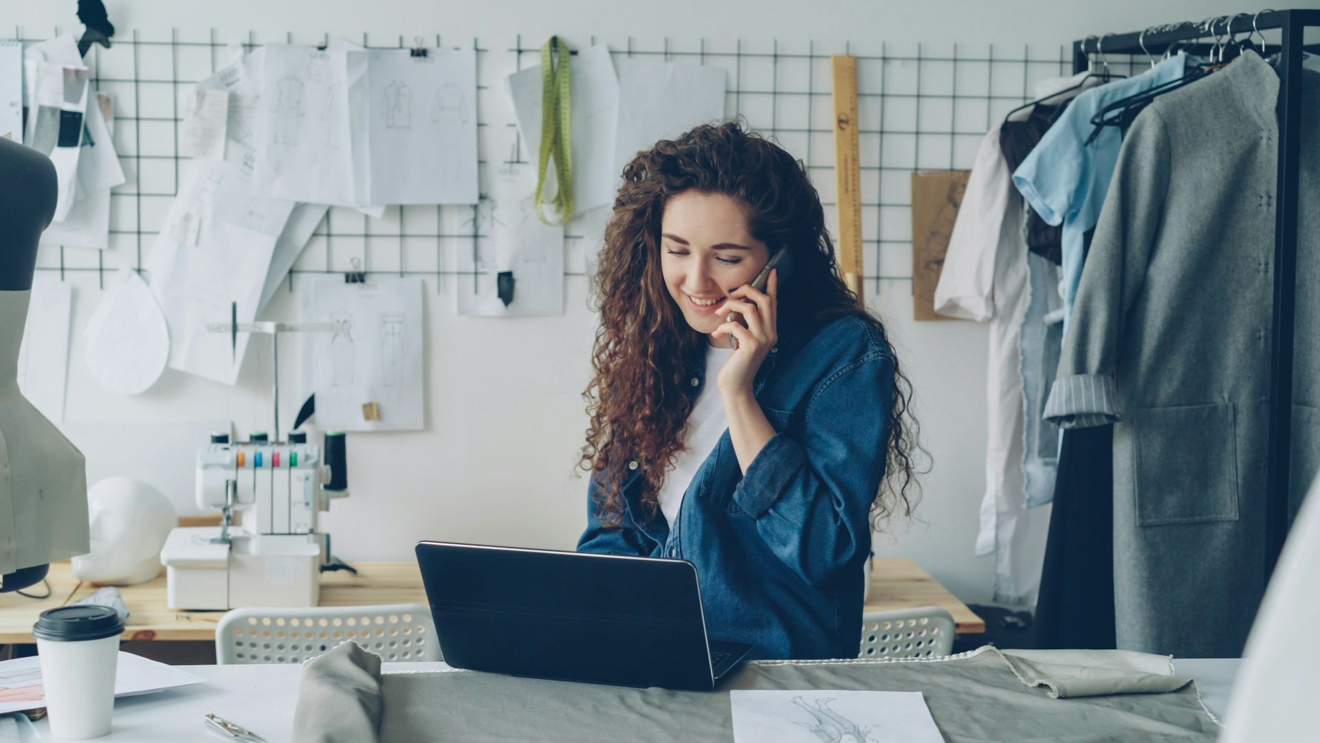 Fashion designer on the phone, working on a laptop.