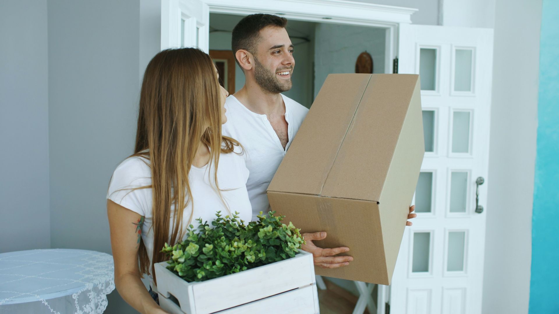 Couple carrying moving boxes into a new home