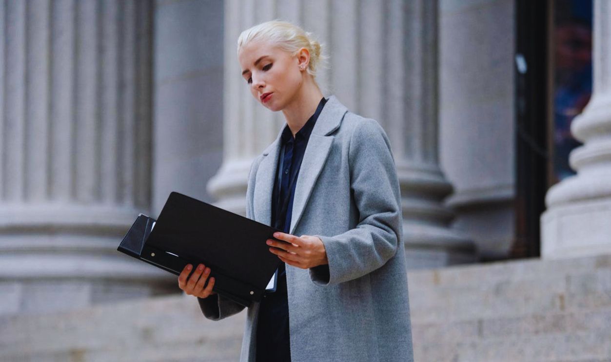 Contemplative businesswoman reading papers in folder outside building