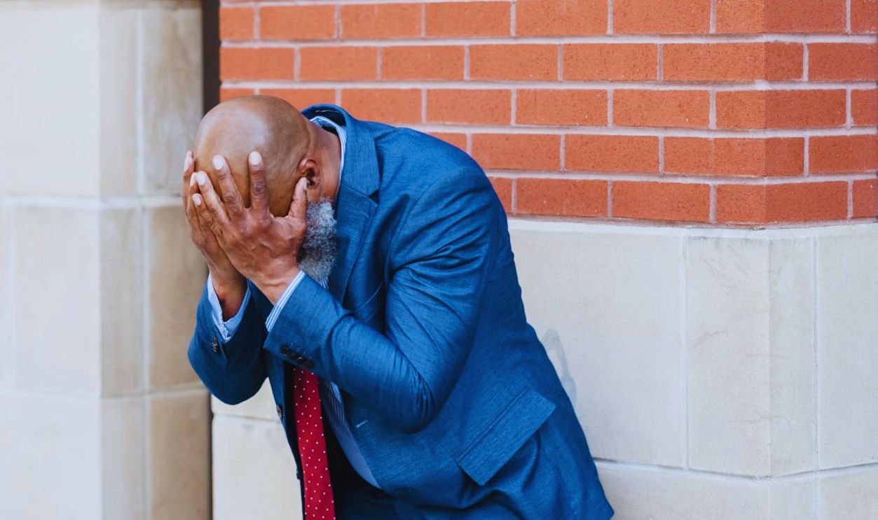Man in Blue Coat Leaning on a Wall