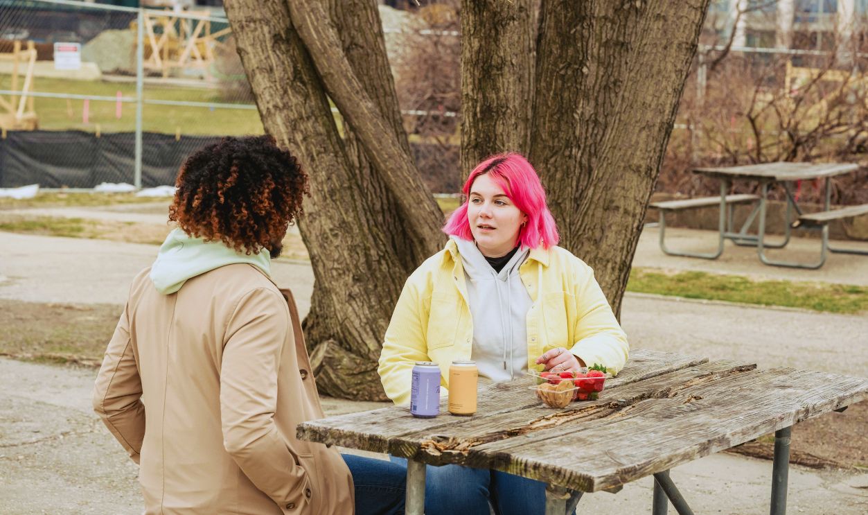 Woman with Pink Hair Seated beside Wooden Table