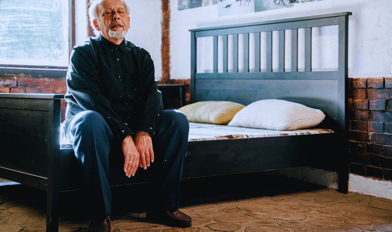 Man in Black Jacket Sitting on Bed