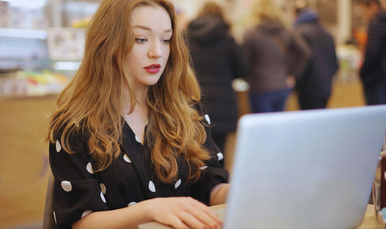 Woman in Black and White Polka Dot Shirt Using Silver Laptop Computer