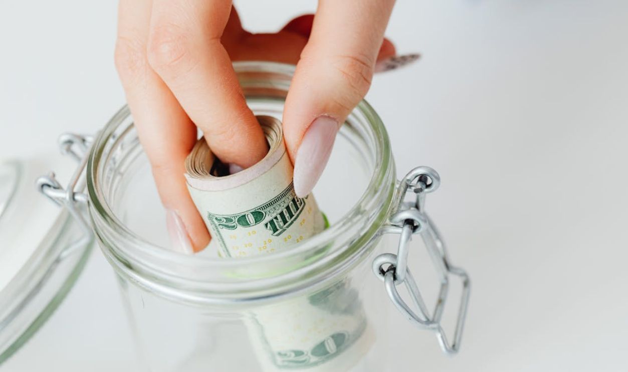 Close-Up Shot of a Person Saving Money in the Glass Jar