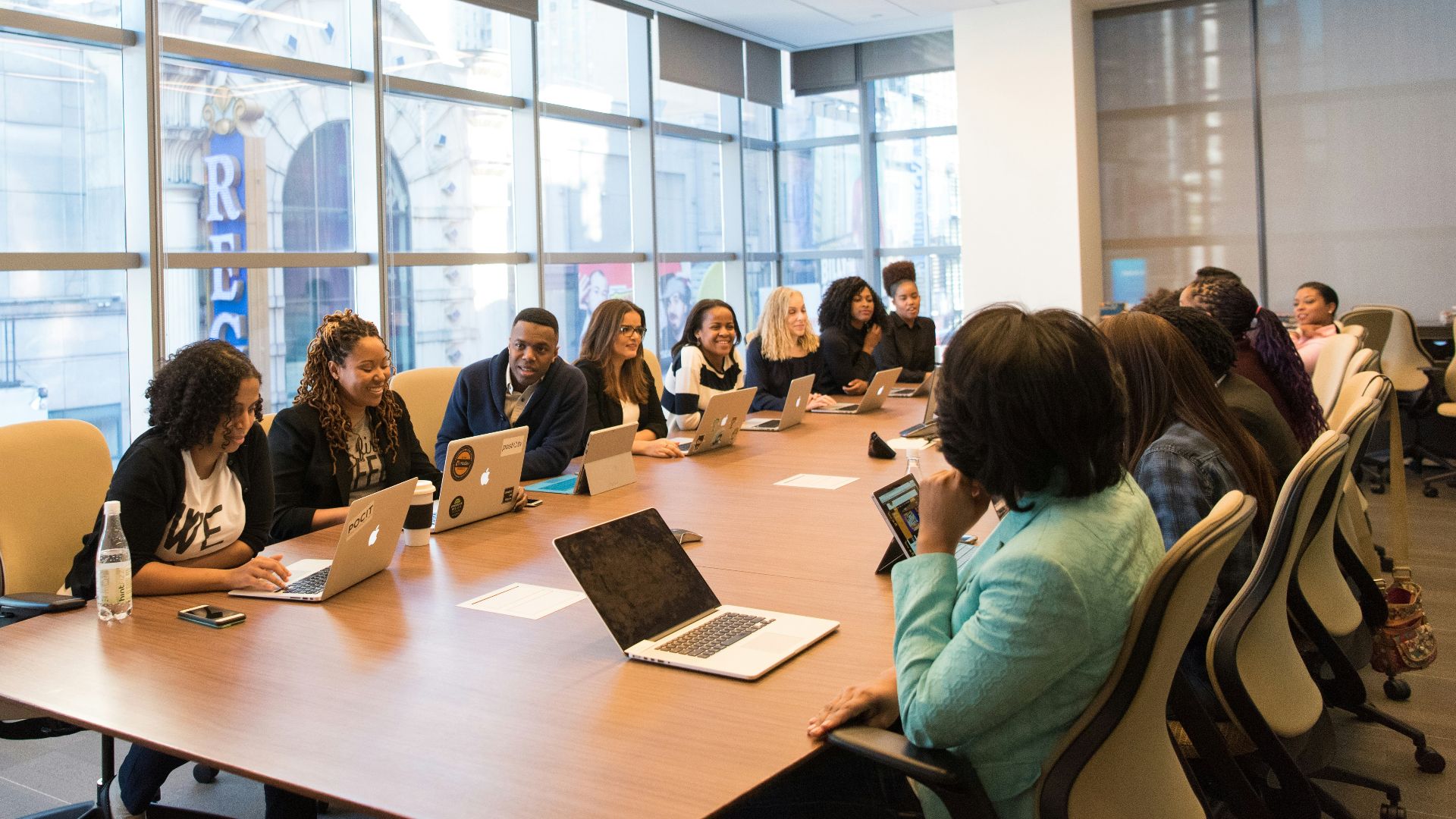 group of people sitting beside rectangular wooden table with laptops