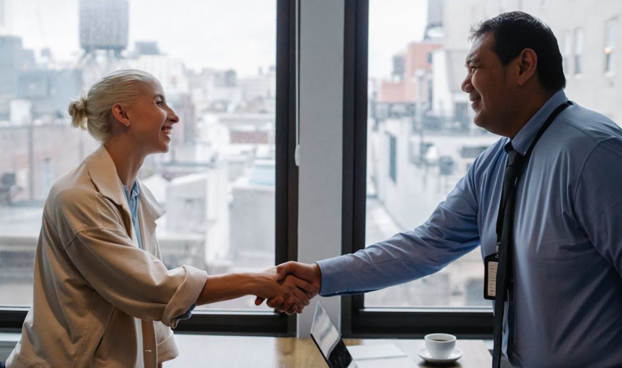 Cheerful colleagues shaking hands while standing at table