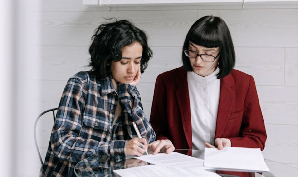 A Woman in Checkered Shirt Signing Documents