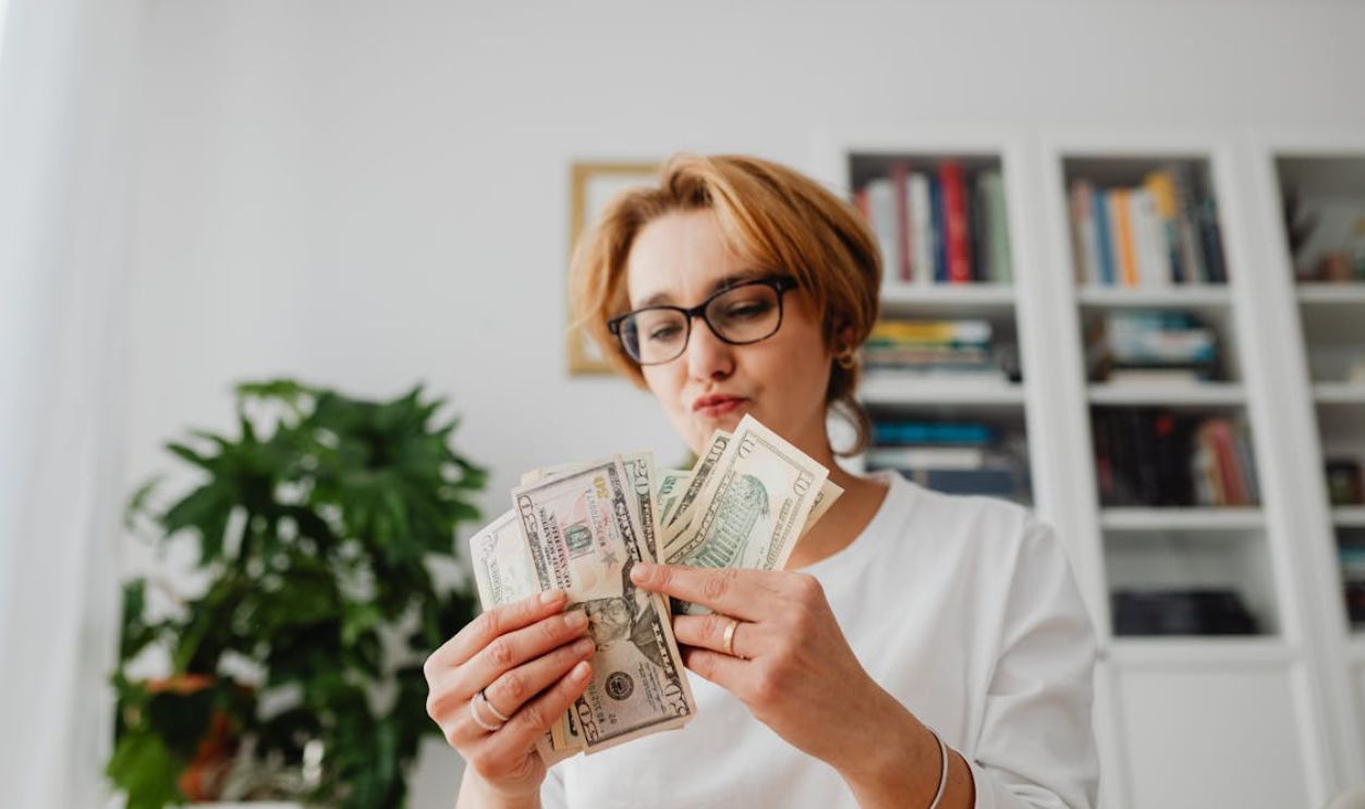 Woman in White Long Sleeve Shirt Holding Counting Dollar Bills