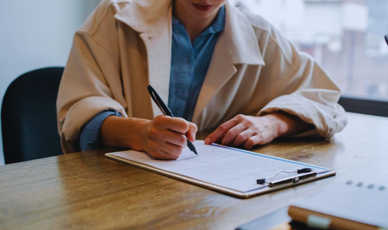 Focused woman writing in clipboard while hiring candidate