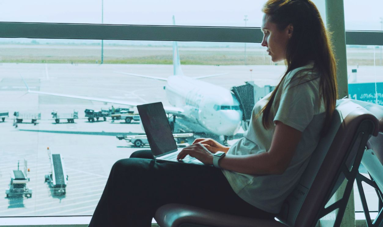 Woman Sitting Near Window While Using a Laptop