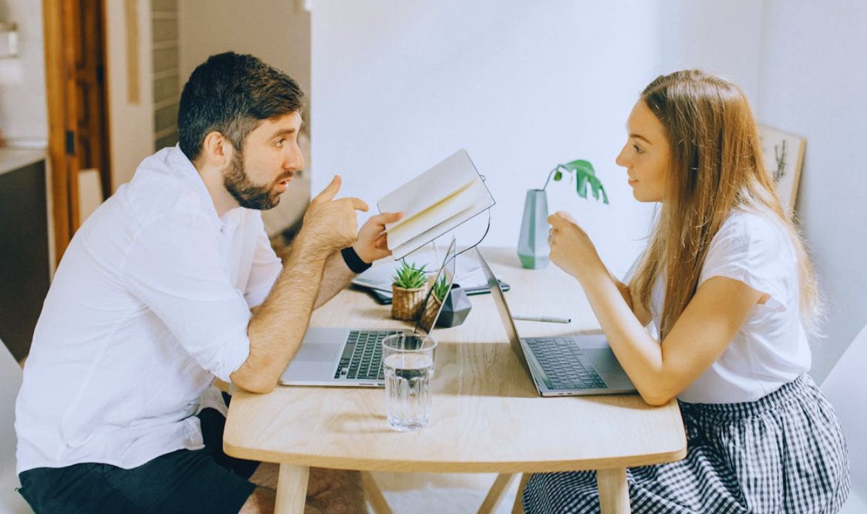 Man and Woman Sitting at Table with Laptops