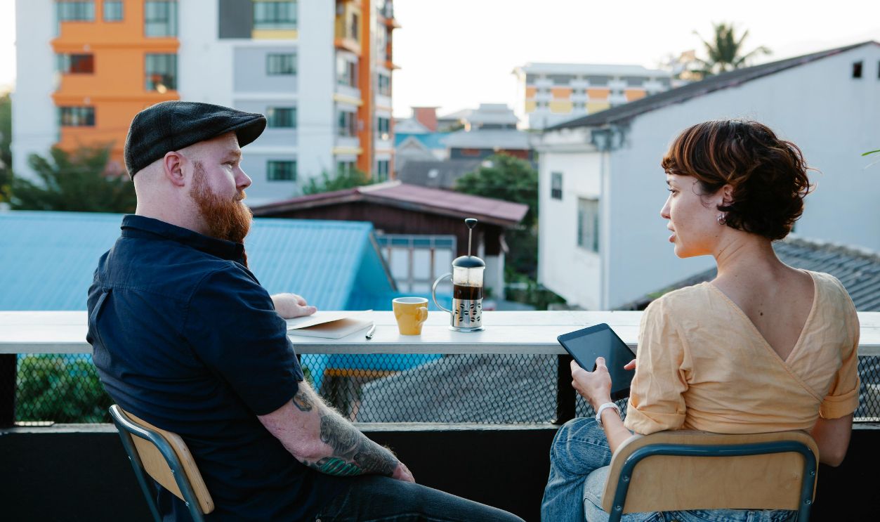 Casual man and woman chatting and resting on terrace