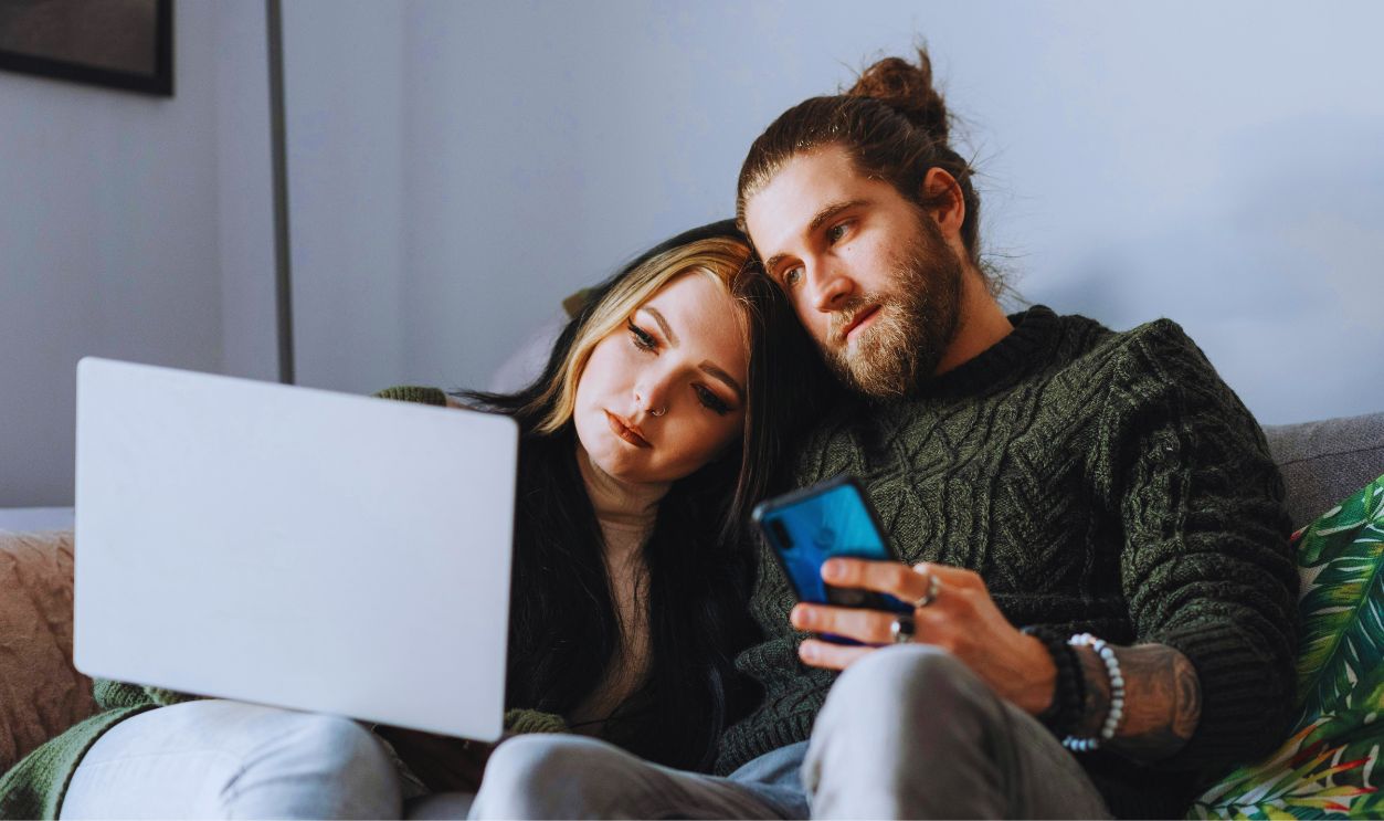 Couple with laptop and smartphone on sofa at home
