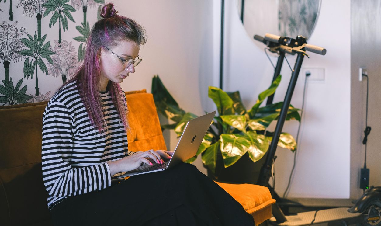 A Woman in a Striped Shirt Typing on a Laptop