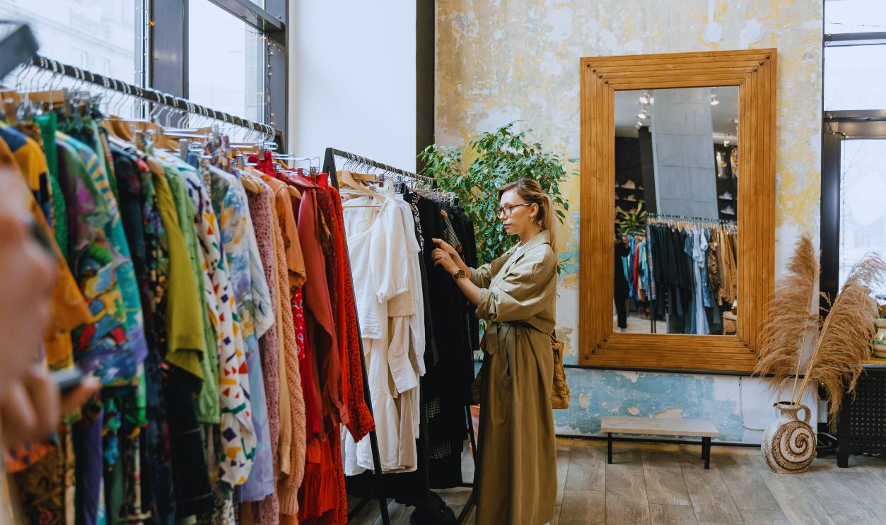 Woman in Brown Trench Trench Coat Standing Near Clothes Rack