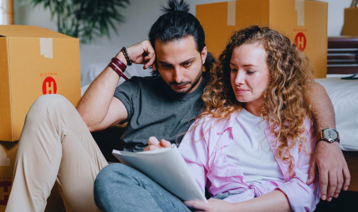 Thoughtful couple writing in notebook while moving house